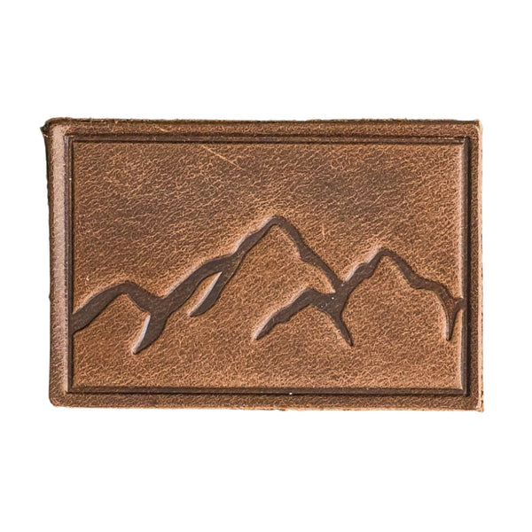 Mountains Range Patch - Cafe Leather, Handmade with High-Quality Full-Grain Leather with Velcro® brand backing, this leather Mountain Range hiking Patch is 2" x 3" sized perfectly for our tactical/ operator caps, backpacks and jackets. Made in the USA.
